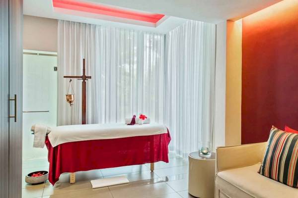 Massageraum im Long Beach Mauritius Hotel mit rotem Massagetisch und weißen Vorhängen.