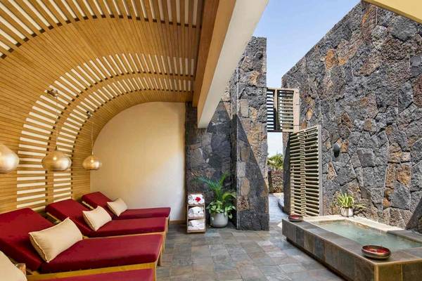 Spa-Bereich im Long Beach Mauritius Hotel mit roten Liegen und Steinwänden.