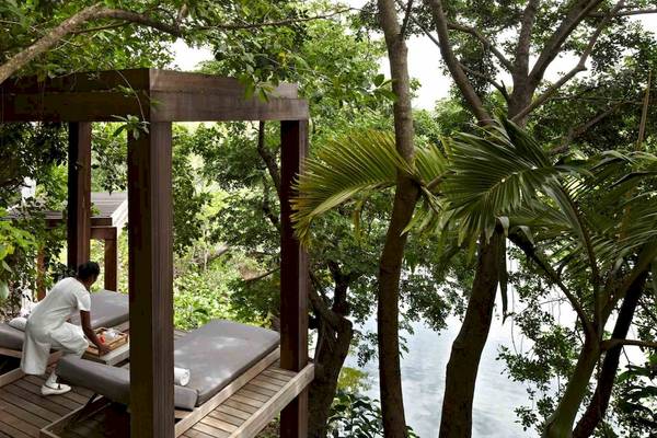 Eine Frau bereitet die Liegen auf der Holzterrasse im Wald des Long Beach Mauritius vor.