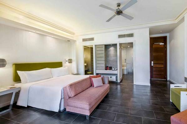 Ein elegantes Hotelzimmer mit einem großen Bett, einer Couch, einem Fernseher und einer Klimaanlage.
