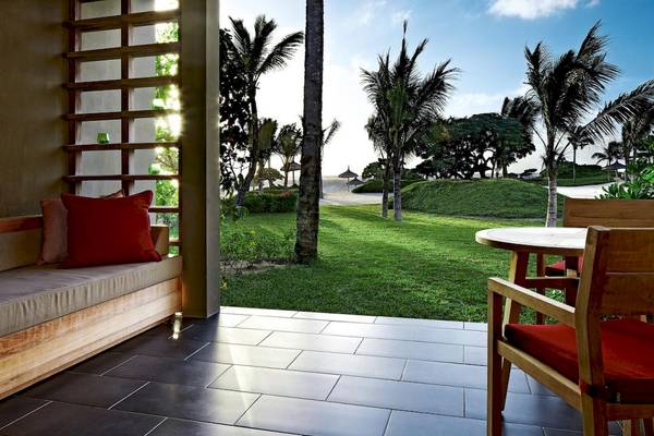 Terrasse des Long Beach Mauritius Hotels mit Blick auf eine Wiese und Palmen