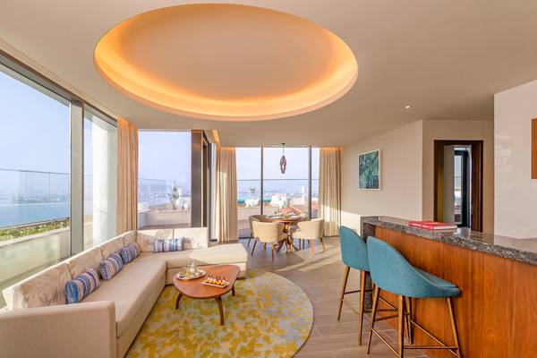 Wohnbereich im Retreat Palm Dubai MGallery by Sofitel mit modernem Design, großer Couch, Tisch und Blick auf die Stadt.