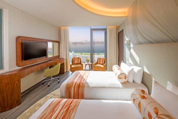 Suite-Zimmer im The Retreat Palm Dubai MGallery by Sofitel mit zwei Betten, Fernseher und Meerblick.