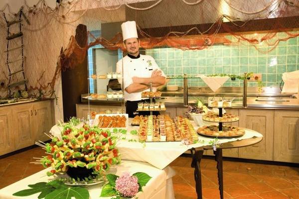 Der Küchenchef des Baia Caddinas Hotels steht vor einem Tisch voller verschiedener Desserts und Gebäck.