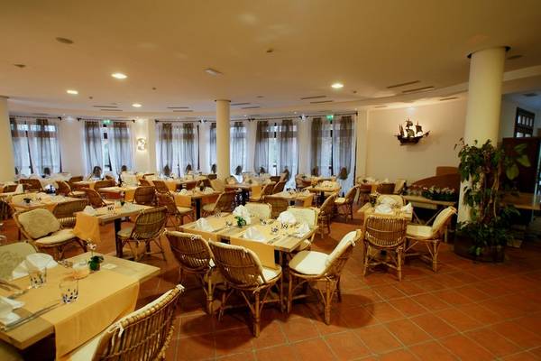 Restaurant im Baia Caddinas Hotel mit vielen gedeckten Tischen und Stühlen.