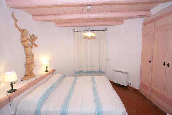 Schlafzimmer im Baia Caddinas Hotel mit Bett, Lampen und rosa Wand