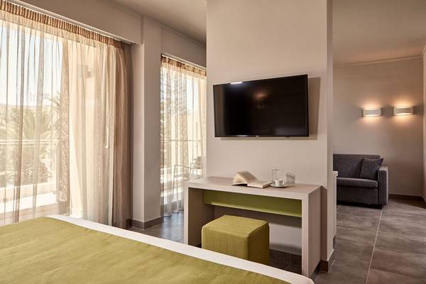 Ein modernes Hotelzimmer mit einem Bett, einem Schreibtisch, einem Fernseher und einer Couch.