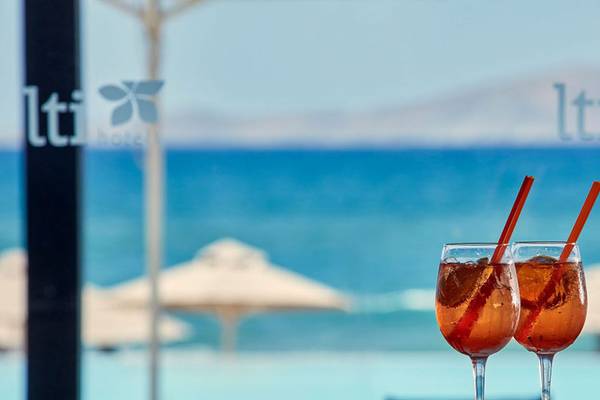 Zwei Cocktails mit Strohhalmen in Gläsern vor einem Pool mit Blick auf das Meer, Marke lti Hotels.
