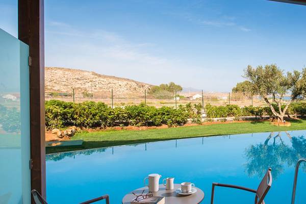 Aussicht auf den Pool im Sentido Unique Blue Resort & Villas mit grüner Rasenfläche und Bäumen