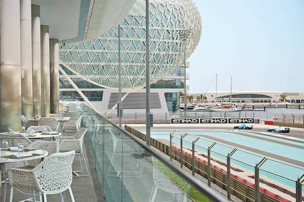 Außenbereich des W Abu Dhabi - Yas Island Hotels mit Blick auf eine Rennstrecke und weißen Stühlen.