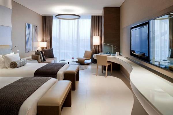 Hotelzimmer im W Abu Dhabi auf Yas Island mit zwei Betten, Wohnzimmerbereich und Fernseher.
