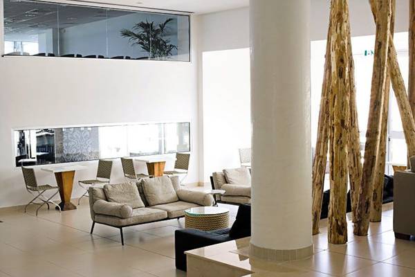 Innenbereich der Lobby im Napa Mermaid Hotel & Suites mit Möbeln, Holzsäulen und Glaswänden.
