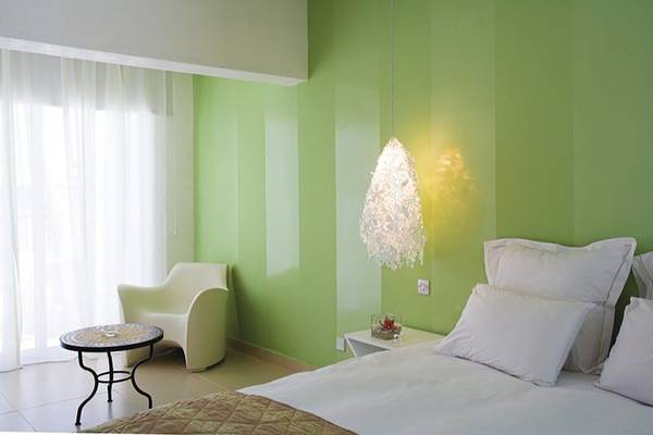 Schlafzimmer im Napa Mermaid Hotel & Suites mit grünen Wänden, Bett, Stuhl und Tisch