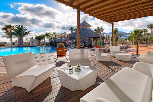 Außenterrasse des H10 Timanfaya Palace mit weißen Möbeln und einem Pool im Hintergrund.