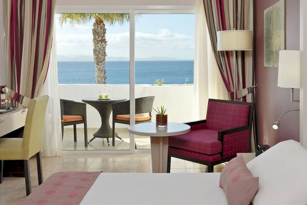 Zimmer im H10 Timanfaya Palace Hotel mit Blick auf das Meer und eine Terrasse.