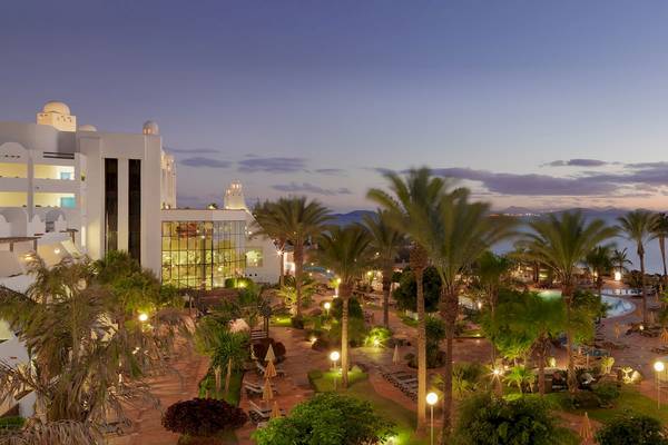 Abendansicht des H10 Timanfaya Palace Hotels mit beleuchteten Palmen und Gebäuden.