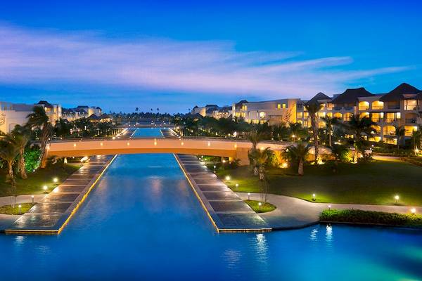 Außenansicht des Hard Rock Hotel & Casino Punta Cana bei Nacht mit Brücke, Wasserkanal und beleuchteten Gebäuden