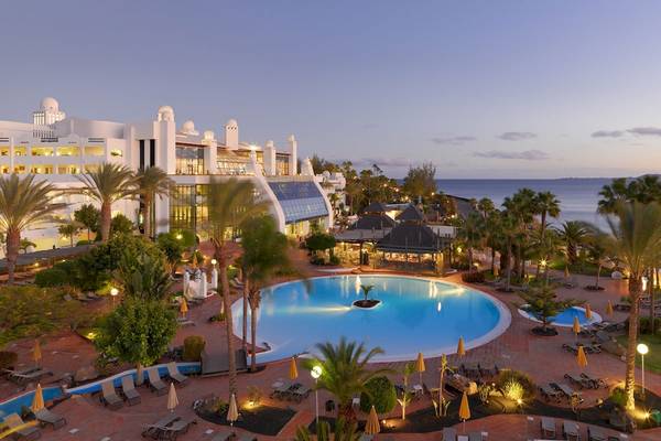 Luftaufnahme des Poolbereichs des H10 Timanfaya Palace Hotels mit Loungestühlen und Palmen