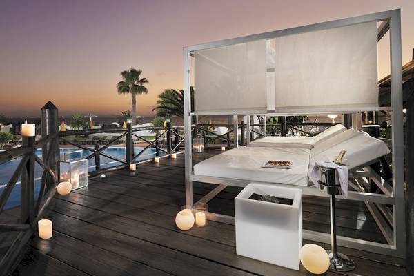 Terrasse des H10 Timanfaya Palace mit Loungebett, Pool und Kerzen bei Nacht
