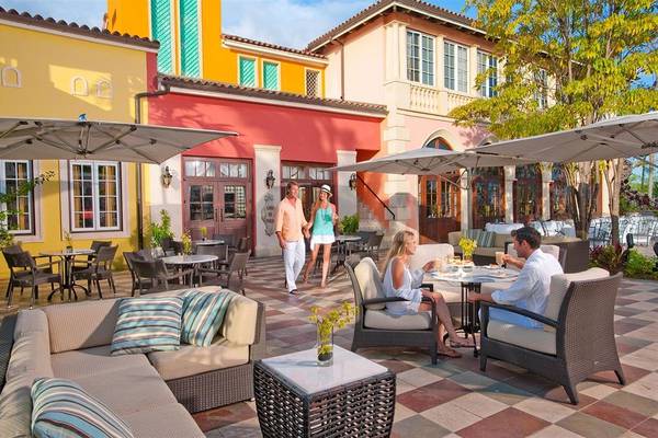 Gäste sitzen auf der Terrasse des Sandals Whitehouse European Village & Spa und genießen das Essen.