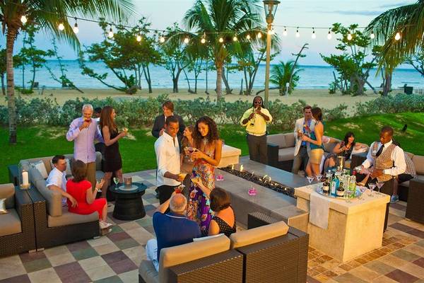 Abendparty im Sandals Whitehouse European Village & Spa mit Gästen, Cocktails und Meerblick.