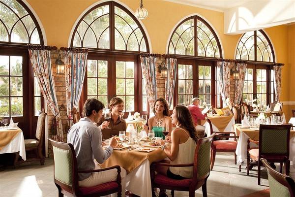 Gäste sitzen an Tischen in einem Restaurant des Sandals Whitehouse European Village & Spa.