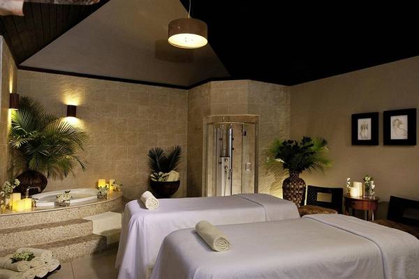 Spa-Behandlungsraum im Sandals Whitehouse European Village & Spa mit zwei Massageliegen, Jacuzzi und Pflanzen.