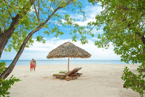 Ein Paar spaziert am Strand des Sandals Whitehouse European Village & Spa.