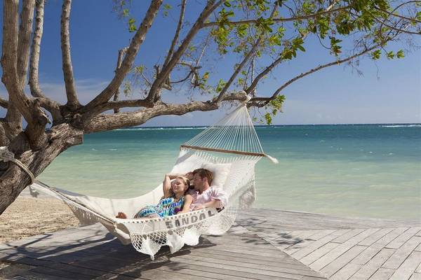 Paar liegt entspannt in einer Hängematte am Strand von Sandals Whitehouse European Village & Spa.