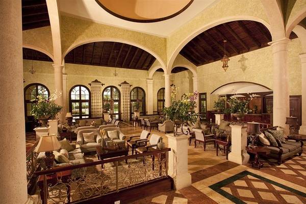 Lobby des Sandals Whitehouse European Village & Spa Hotels mit eleganten Möbeln, Pflanzen und Deckenlampen.