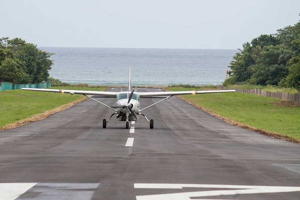 Ein Flugzeug auf dem Rollweg eines Flugplatzes mit dem Meer im Hintergrund.
