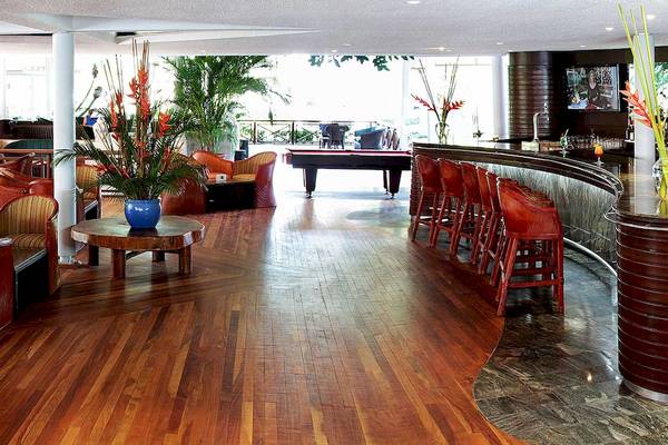Innenansicht der Lobby-Bar des Barcelo Tambor Hotels mit Holzboden, roten Stühlen, Tisch mit Pflanze und Billardtisch.