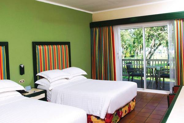 Zwei Betten im Hotelzimmer des Barcelo Tambor mit grünen Wänden und bunten Kopfteilen.