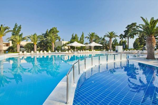 Außenpool des Kipriotis Hippocrates Hotels mit weißen Sonnenliegen und Palmen