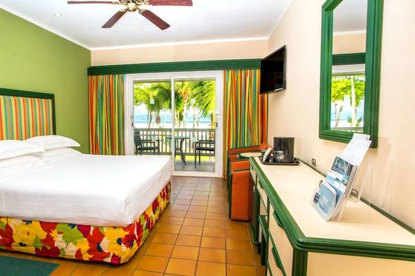 Hotelzimmer im Barcelo Tambor mit grünen Wänden, buntem Kopfteil, Doppelbett und Balkonzugang.