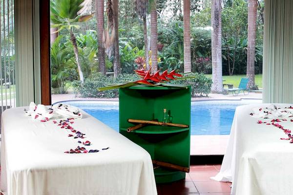 Zwei Massageliegen mit weißen Decken und Blumendekor stehen nebeneinander mit Blick auf einen Pool im Barcelo Tambor.