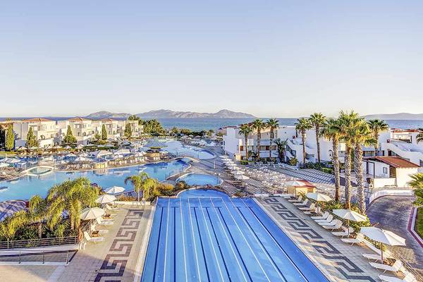 Außenansicht des Atlantica Marmari Palace Resorts mit Pools, Liegestühlen und Palmen.