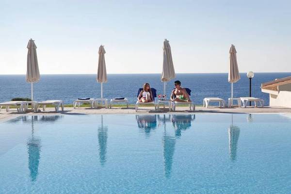 Zwei Personen, die an einem Pool mit Meerblick sitzen, Blau Punta Reina Hotel