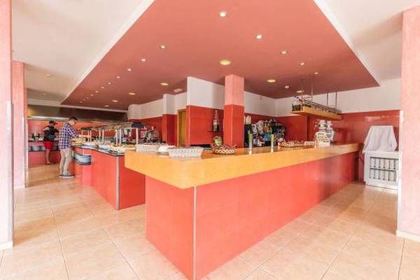 Innenansicht des Blau Punta Reina Hotel Restaurants mit roten Wänden und gelber Theke.