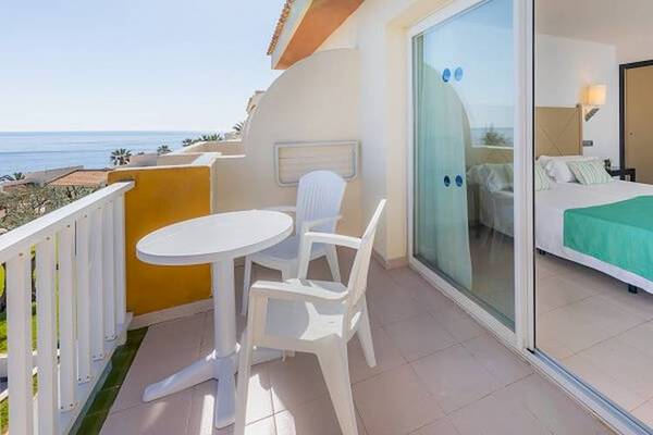 Blick auf einen Balkon des Blau Punta Reina Hotels mit Meersicht, einem Tisch und Stühlen.