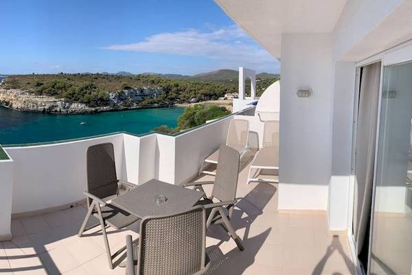 Blick vom Balkon des Blau Punta Reina Hotels auf das Meer und eine Klippe.