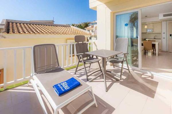 Balkon des Blau Punta Reina Hotels mit Tisch, Stühlen und Sonnenliegen.
