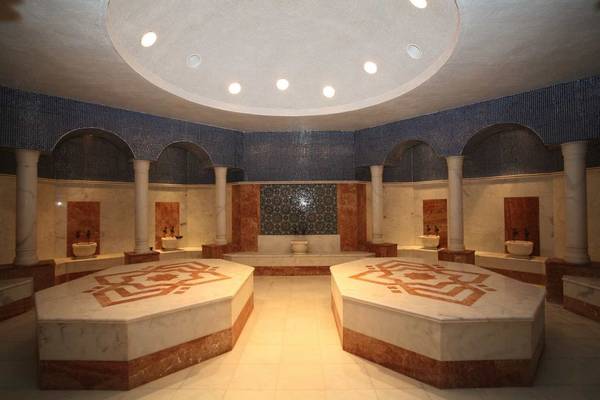 Innenansicht des Spa-Bereichs im Sunis Kumköy Beach Resort & Spa mit Marmorböden und gemusterten Bänken.