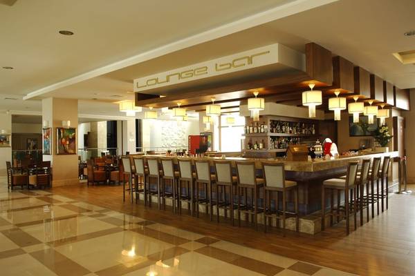 Lounge Bar im Sunis Kumköy Beach Resort & Spa mit Holzbar, Stühlen und gemustertem Boden.