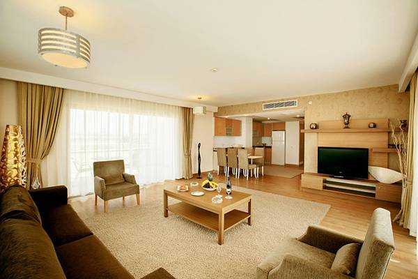 Innenraum des Wohnzimmers im Sunis Kumköy Beach Resort & Spa mit Möbeln, Fernseher und Esstisch.