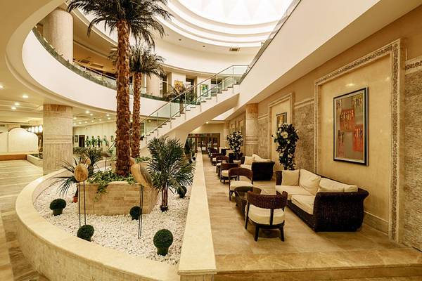 Lobby des Sunis Kumköy Beach Resort & Spa mit einem zentralen Palmbaum, Sitzbereichen und Treppen