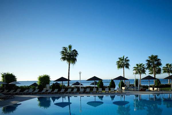 Außenpool des Atlantica Miramare Beach Hotels mit Sonnenliegen und Palmen.