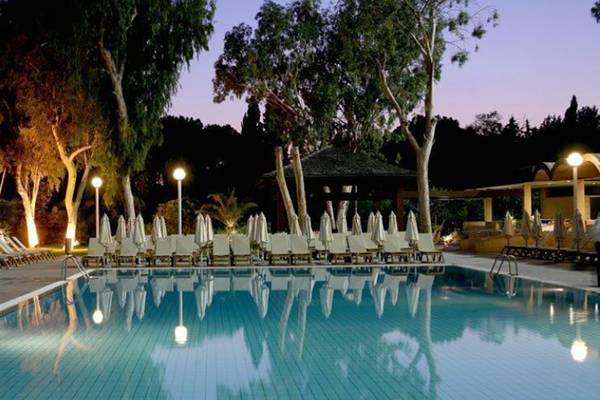 Abendansicht des Schwimmbeckens im Atlantica Miramare Beach Hotel mit illuminierten Liegen und Schirmen
