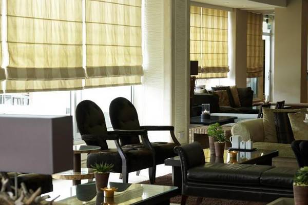 Frau sitzt in der Lobby des Atlantica Miramare Beach Hotel mit Kaffeetasse