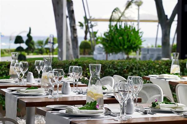 Gartentisch des Atlantica Miramare Beach Hotels, gedeckt mit Geschirr und Gläsern.